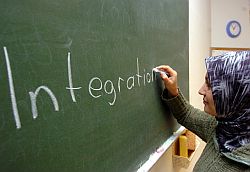 Türkische Frau schreibt das Wort "Integration" an eine Tafel. Klick vergrößert Bild