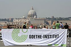 Ein Transparent des Goethe-Instituts vor Stadtkullisse Roms, Klick vergrößert Bild