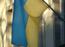 Foto: Ukrainische Flagge am Mast vor einem Fenster