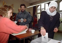 Eine türkische Frau wirft in einem Wahllokal ihren Stimmzettel in die Wahlurne, Klick vergrößert Bild