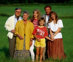 Eine Großfamilie mit drei Generationen steht auf einer grünen Wiese.