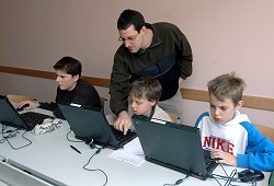 Lehrer zeigt Schülern etwas an einem Laptop.