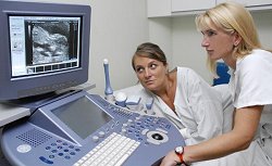 Frauenärztin und Schwangere vor Ultraschallgerät, Klick vergrößert Bild