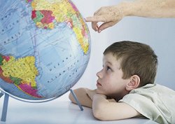Ein Kind läßt sich auf einem Globus etwas erklären.