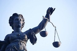 Eine Statue der Justitia, Göttin der Justiz, der Rechtsprechung und der Gerechtigkeit, hält eine Waage mit zwei Wagschalen in der linken Hand