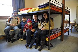 Die Familie Jousif aus dem Irak sitzen auf einem Bett in ihrem Zimmer in einem Übergangswohnheim in München (Oberbayern).