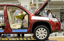 Zwei Mitarbeiter der Volkswagen AG fertigen einen Tiguan in der Produktionsstraße.