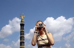 Eine junge Frau macht am Großen Stern in Berlin-Tiergarten im Bezirk Mitte in Berlin ein Foto.