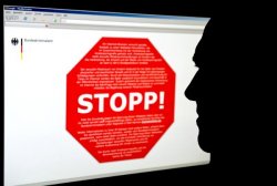 Ein Mann sitzt vor einem Computerbildschirm mit einer wegen des Verdachts der Kinderpornografie gesperrten Internetseite.