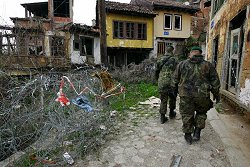 Zwei Bundeswehrsoldaten vor im Krieg zerstörten Häusern in Prizren im Kosovo.
