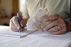Rentner mit Geld in der Hand beim Schreiben, Klick vergrößert Bild