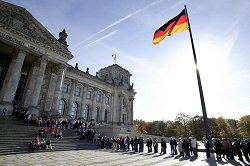 Vor dem Reichstagsgebäude steht eine Besucherschlange, die Deutschland-Fahne ist zu sehnen.