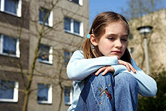 Ein kleines Mädchen sitzt allein in einem Neubaugebiet