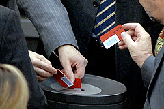 Abgeordnete werfen Stimmkarten in Urne