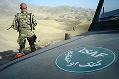 Soldat hinter Geländefahrzeug mit Emblem "ISAF"