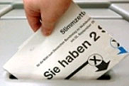 Ein Stimmzettel wird in eine Wahlurne gesteckt.