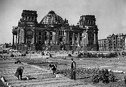 1946: Ansicht des kriegszerstörten Reichstagsgebäudes; im Vordergrund Kleingartenkolonie auf dem abgeholzten Tiergartengelände.