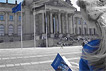 Ein junge Frau steht mit dem Grundgesetz in der Hand vor dem Reichstagsgebäude.