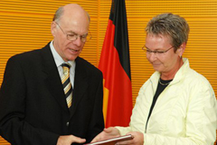 Vorsitzende Naumann (rechts) übergibt den Bericht an Bundestagspräsident Lammert.