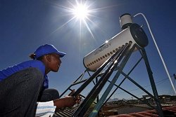 Ein Mann installiert eine Solaranlage zur Wassererwärmung auf dem Dach.