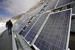 Ein Mitarbeiter der Umweltforschungsstation Schneefernerhaus auf der Zugspitze bei Garmisch-Partenkirchen steht vor einer Solaranlage auf dem Dach des Gebäudes.