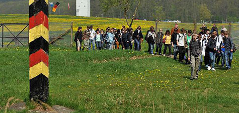 Schler passieren einen ehemaligen Grenzpfahl 