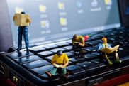 Minifiguren sitzen auf einer Laptop-Tatstatur und lesen