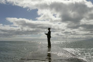 Mann mit Laptop steht am Meer