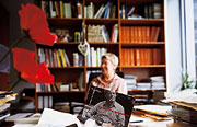Bild: Petra Merkel hinter ihrem Schreibtisch. Im Hintergrund ist ein großes Bücherregal zu sehen.