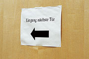 Bild: Zettel mit Pfeil und der Aufschrift: Eingang nächste Tür.