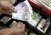 Bild: Hände mit Geldscheinen vor einer offenen Kassenlade.
