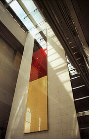 Bild: Sehr hohe und schmale Fläche in den Farben Schwarz, Rot, Gold, an einer Wand