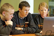 Bild: Zwei Jungen und ein Mädchen vor einem Computer. Sie spielen das Strategiespiel Ecopolicy.