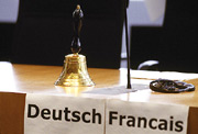 Bild: Tisch mit Glocke und Papierblätter mit den Aufschriften Deutsch und Francais