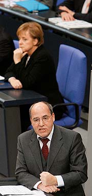 Bild: Gregor Gysi, Fraktionsvorsitzender Die Linke., redet während einer Parlamentsdebatte, Kanzlerin Merkel im Hintergrund.