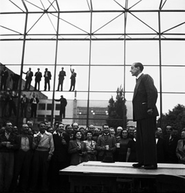 Mann beim Richtfest zum Bau des Plenarsaals des Bundestages, im Hintergrund Arbeiter im Stahlgerüst