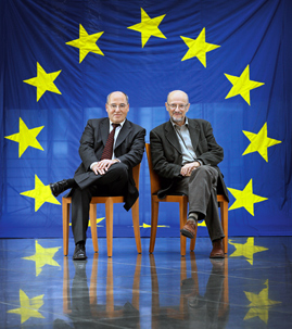 Gregor Gysi und Adam Krzeminski sitzend auf Stühlen vor einer Europaflagge