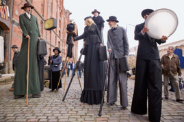 Schauspieler in historischer Kleidung auf Stelzen vor einem Backsteinhaus in der Hamburger Speicherstadt