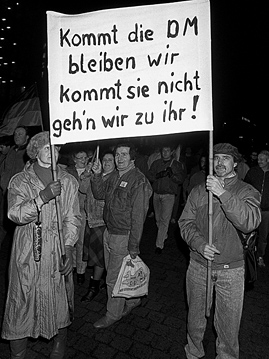 Ein Paar auf der Montagsdemonstration am 12. Februar 1990 in Leipzig mit einem Transparent, das die Währungsunion fordert