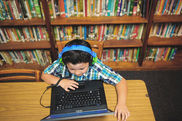 Kind in der Bibliothek am Laptop