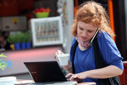 Frau arbeitet mit Handy und Laptop im Cafe