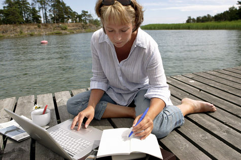 Frau arbeitet auf einem Bootssteg an einem Laptop