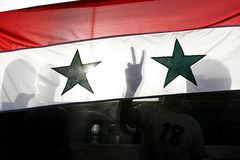 Demonstranten mach Victory-Zeichen hinter syrischer Landesfahne
