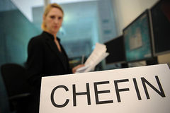 Frau sitzt hinter Schild Chefin