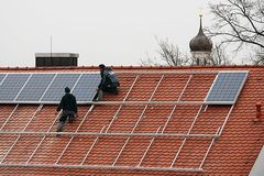 Arbeiter installieren Solarzellen auf einem Dach.