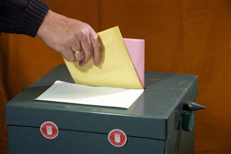 Stimmzettel werden Wahlurne geworfen