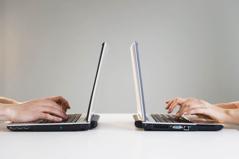 Zwei Laptops mit tippenden Fingern