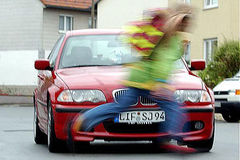 Schulkind läuft knapp vor einem Auto über die Straße 