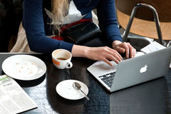 Junge Frau sitzt in einem Cafe und benutzt einen Laptop.