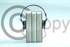 Kopfhörer umgreift drei Bücher